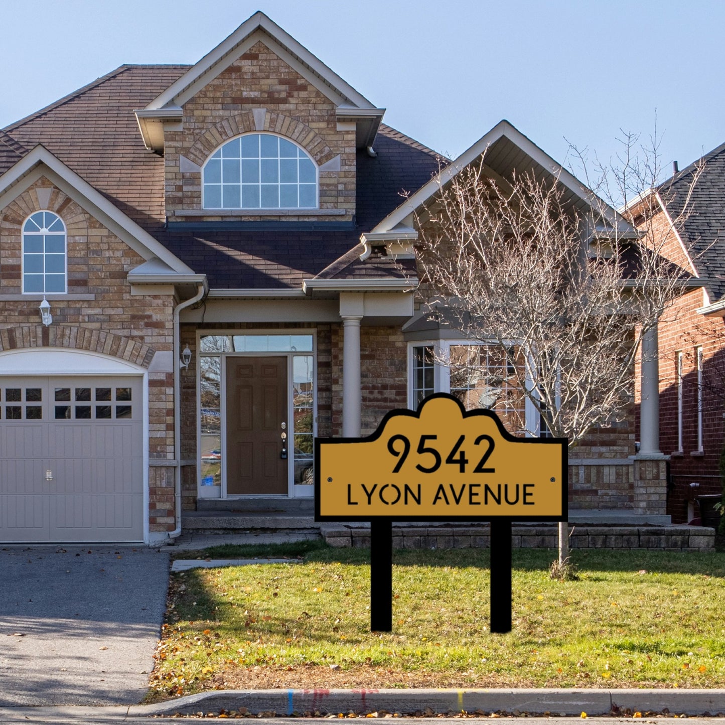 In the front yard of a lovely brick house, the Double Layer Luxury Address Yard Sign stands out. The sign stands out because of its stylish, layered design and warm, gold front panel that is surrounded in bold black. It looks classy and interesting.