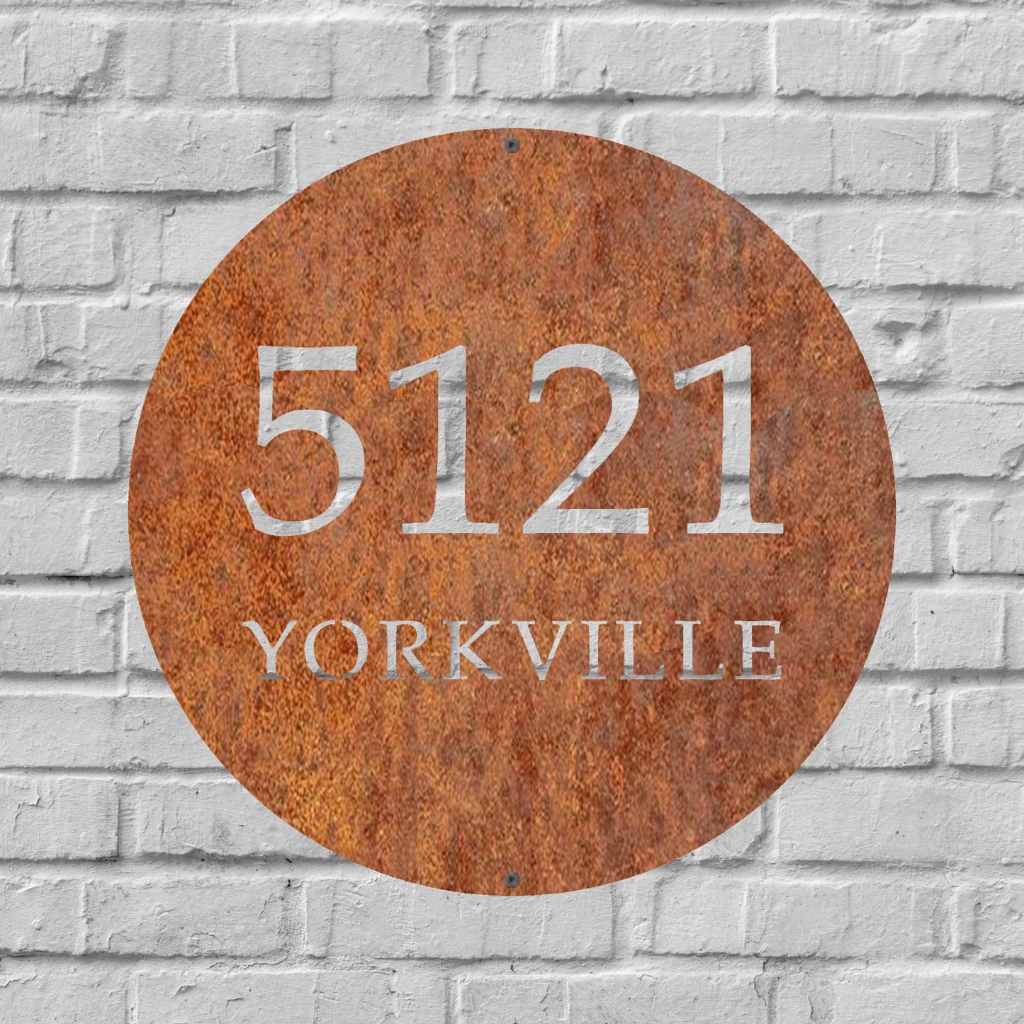 A circular rusted steel address sign displaying "5121 YORKVILLE" in bold white lettering, featuring an elegant serif font