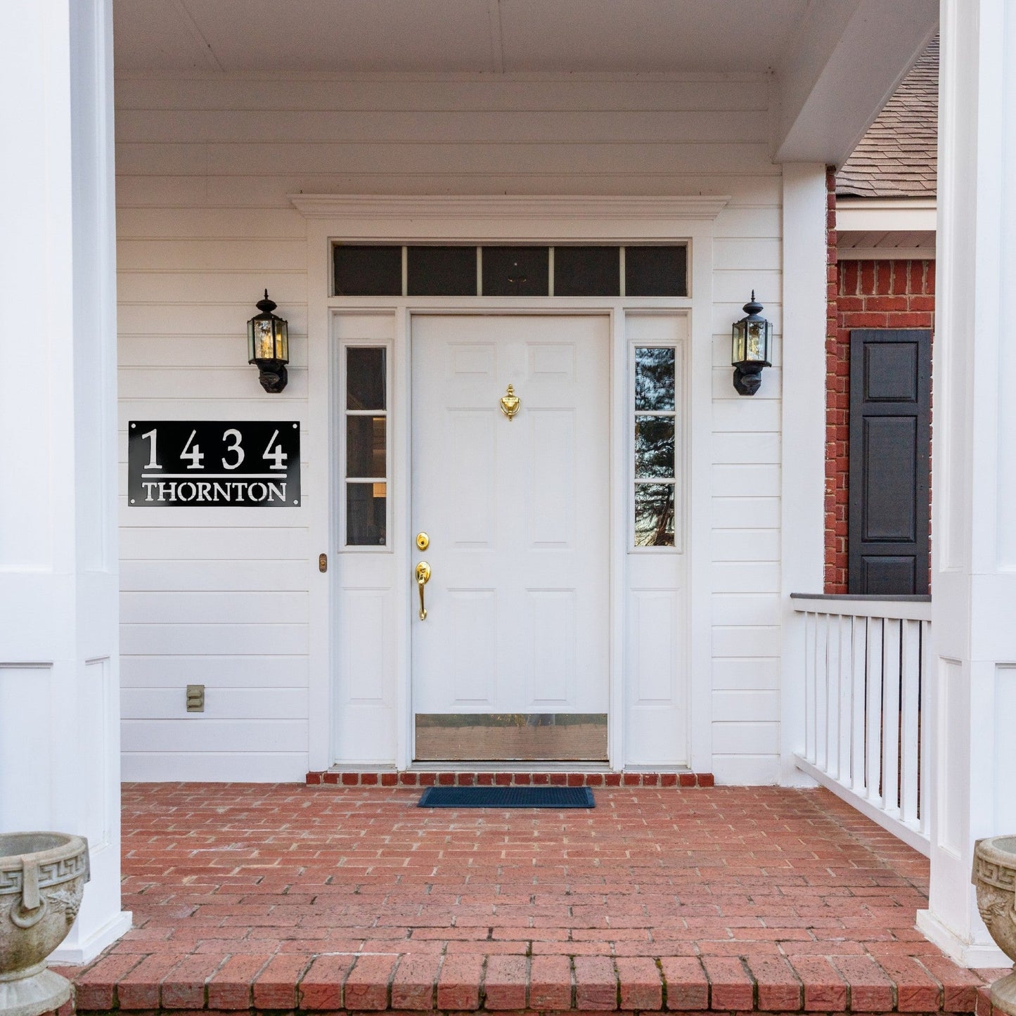 Front Door of a white house with a black home address sign to the left of the door