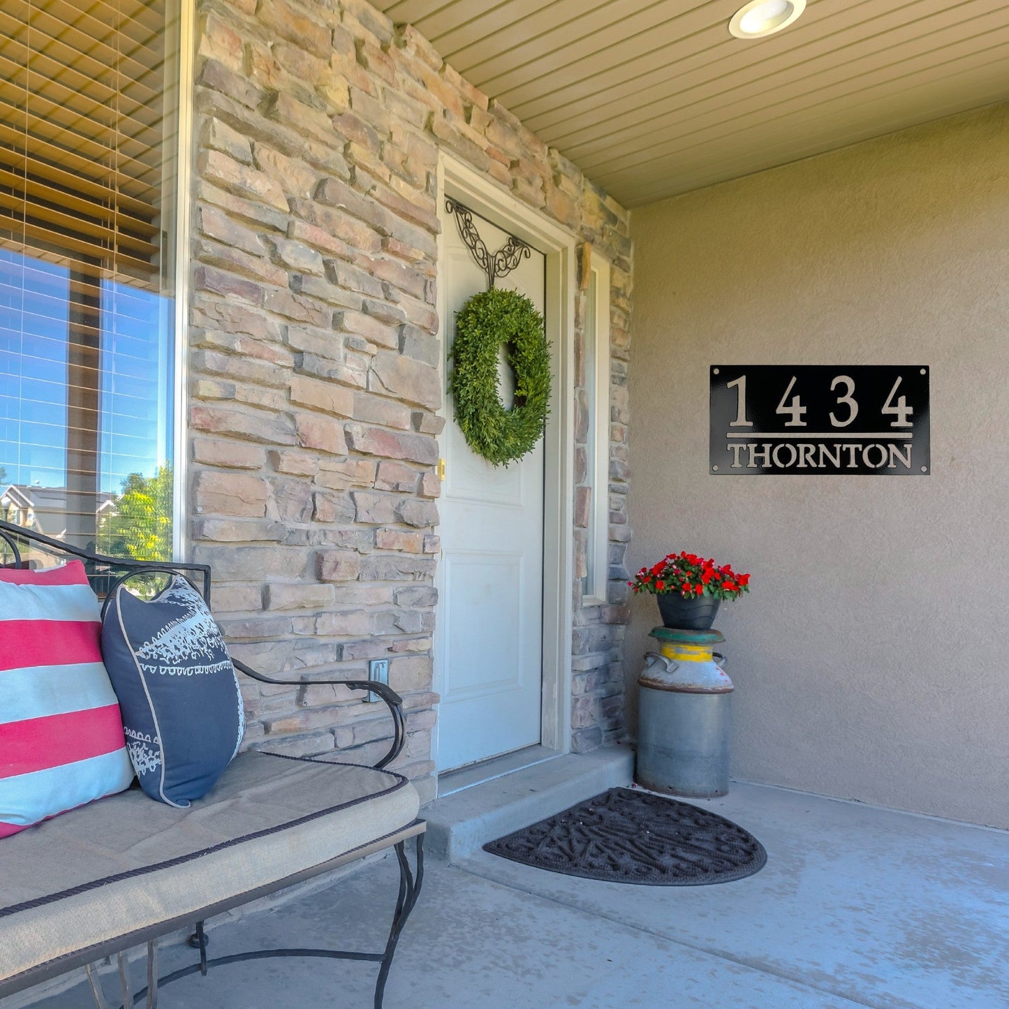 Front porch of a house with a black home address plaque on the wall