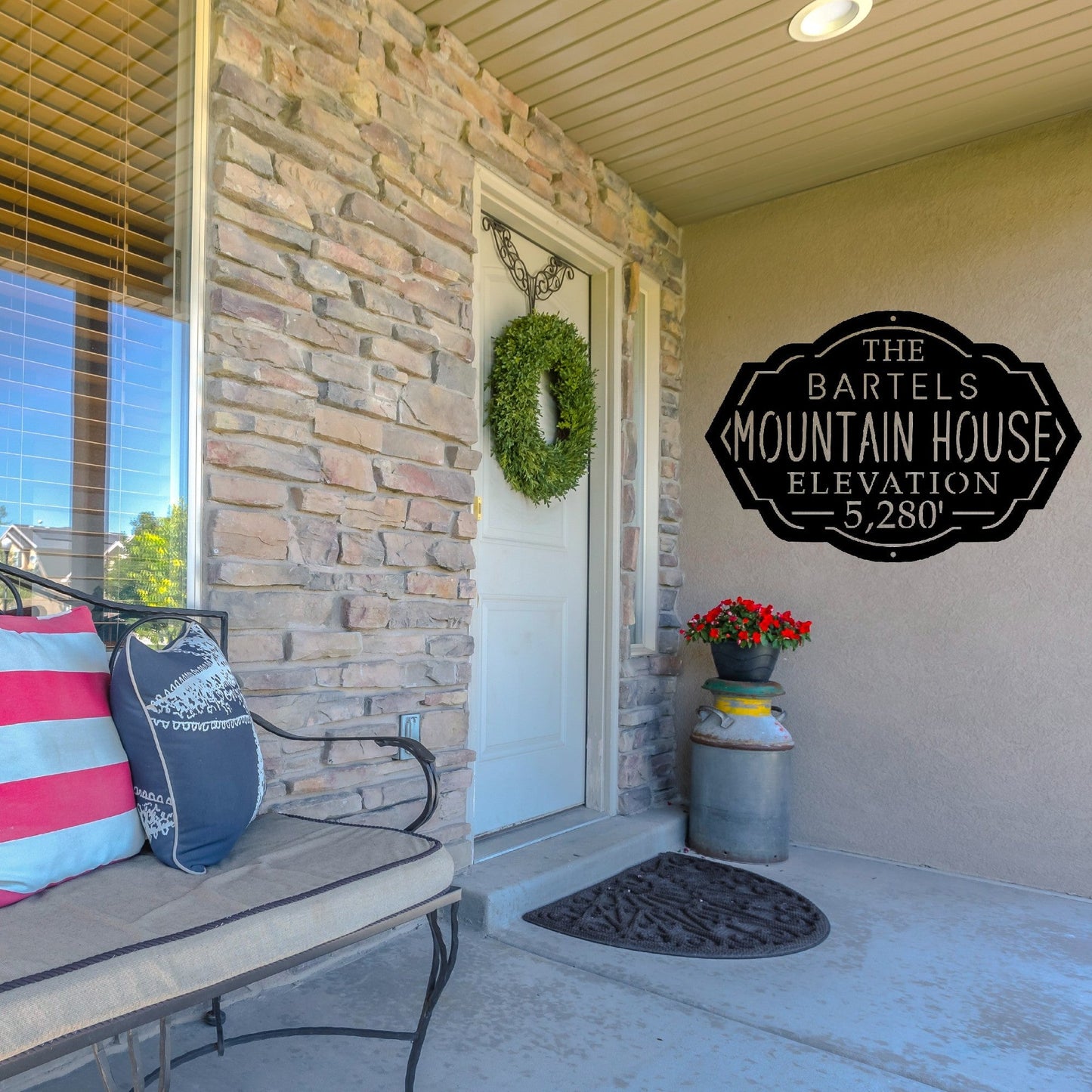 Front porch of a house with a custom metal mountain house sign on the wall