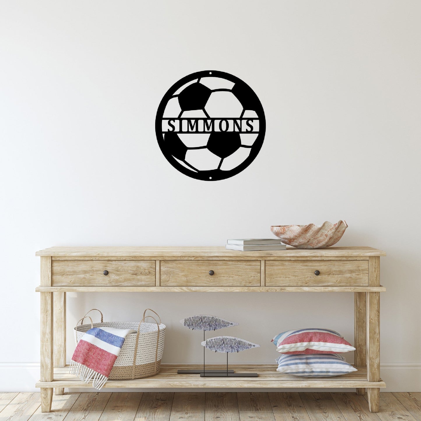 Wooden table with some items on it and a custom metal sign in the shape of a soccer ball on the wall above it