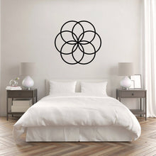 Load image into Gallery viewer, The Cerelia Metal Circles Wall Decor is gracefully hung on the wall above a pristine white bed, creating a visually stunning contrast. The interconnected circles, add a modern, geometric touch that complements the minimalist and clean aesthetic of the room.