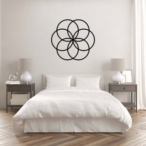 The Cerelia Metal Circles Wall Decor is gracefully hung on the wall above a pristine white bed, creating a visually stunning contrast. The interconnected circles, add a modern, geometric touch that complements the minimalist and clean aesthetic of the room.
