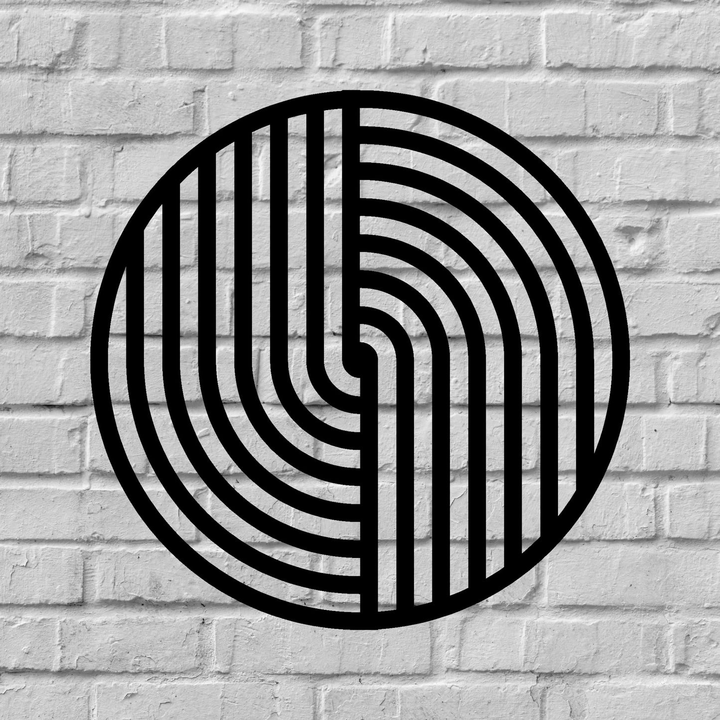 The image features a round metal wall art piece with a bold black geometric pattern, mounted on a textured white brick background. The contrast between the sleek, modern design of the artwork and the rustic, industrial feel of the brick wall creates a visually striking and stylish aesthetic.