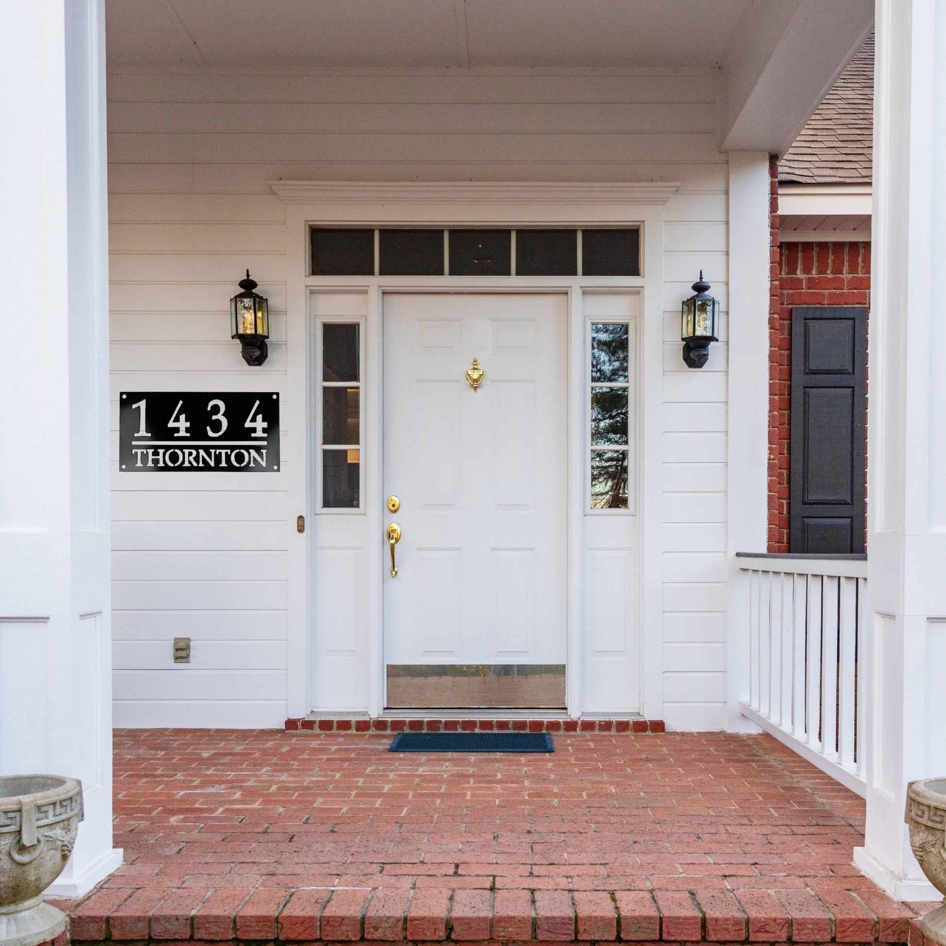 Front Door of a white house with a black home address sign to the left of the door