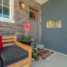 Load image into Gallery viewer, Front porch of a house with a bronze gold home address sign on the wall