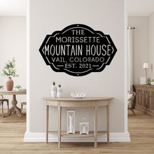 Load image into Gallery viewer, Front entryway of a house with a custom metal sign for a mountain house on the wall above a table