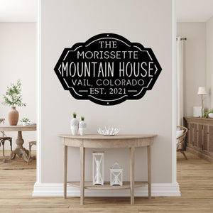 Front entryway of a house with a custom metal sign for a mountain house on the wall above a table