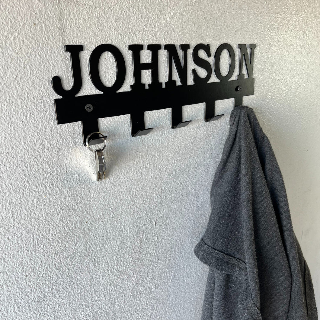 custom name coat rack on a wall with keys and a coat hanging off of it