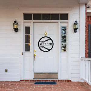 Front door of a house with a white door and a black custom metal sign in the shape of a baseball on the door