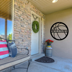 Front porch of a house with a custom metal sign in the shape of a basketball next to the door 